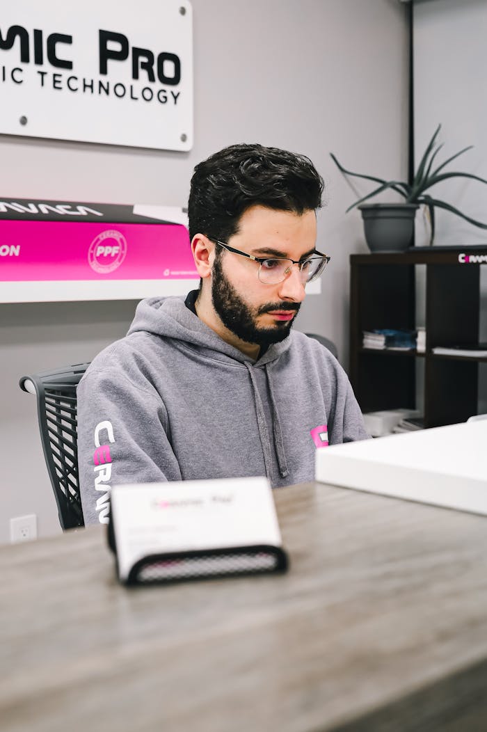 Man in grey hoodie working attentively at a tech company reception desk.